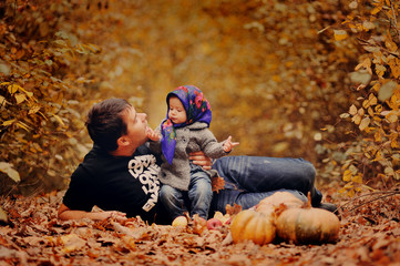 Молодой отец играет со своей маленькой дочерью в осеннем лесу