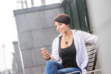 outdoor portrait of young happy smiling woman talking by cell phone in city, urban background