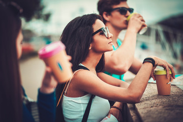Multi-ethnic friends tourists with map and coffee cups near river in a city