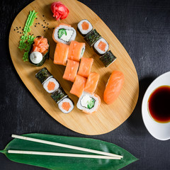 Asian food background. Top view. Flat lay. Japanese food - sushi rolls and sauce on a black background.