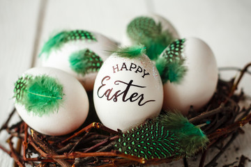 Beautiful Easter background with eggs in the nest and wishes for a happy Easter