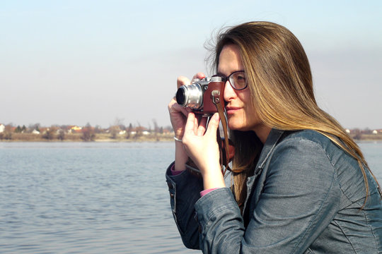 Young woman adjusts vintage retro camera for photos