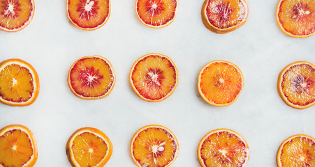 Fototapeta na wymiar Natural fruit pattern. Fresh juicy blood orange slices over light marble table background, top view