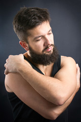 Bearded man hugging himself