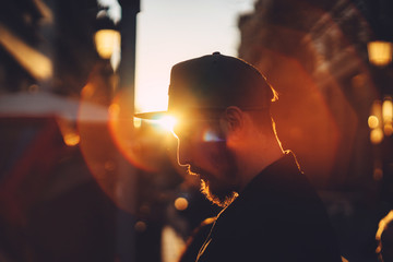 Young businessman working standing near skyscraper office at sunset, Portrait of hipster man in city centre at sunset, sunset light, golden light, soft focus - obrazy, fototapety, plakaty