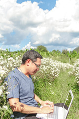 Naklejka na ściany i meble Asia man use laptop in Chrysanthemum field background sky blue.