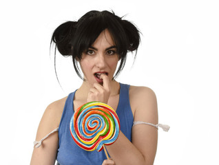 sexy woman with ponytails biting her lips holding and licking sweet caramel big lollipop