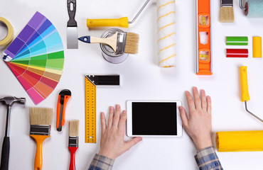 Decorator using a digital tablet. Color swatches and painting tools all around on table