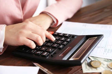 Woman sitting at table with calculator and documents