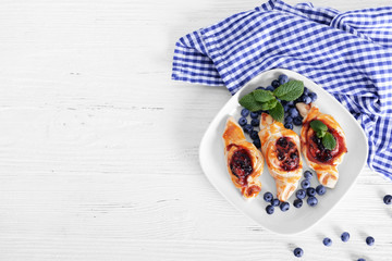 Sweet tasty pastries and fresh bilberries on plate, top view