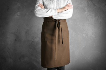 Woman wearing apron on color background