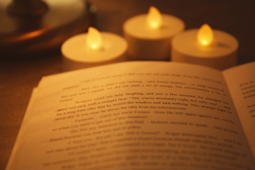 Close up view of book with blurred candles on background