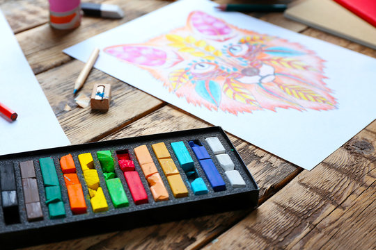 Colouring pictures and pencils on wooden table, closeup
