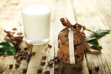 Homemade cookies, glass of milk and coffee beans on wooden table