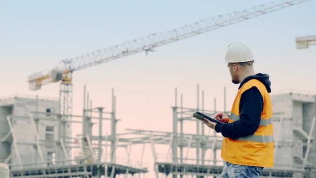 young engineer with the tablet controls the work on site
