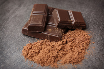 Chocolate with cocoa powder on grey background