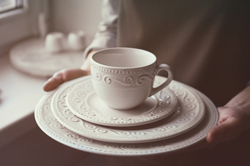 Female hands holding pile of dishware, closeup