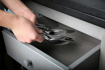 Woman putting silverware into drawer, closeup