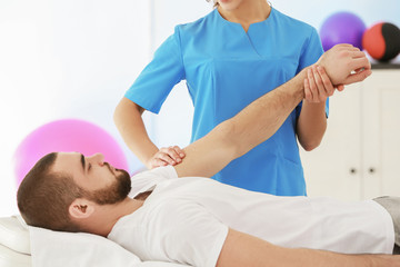 Physiotherapist working with patient in clinic - obrazy, fototapety, plakaty