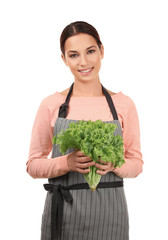 Young woman in apron holding bunch of fresh lettuce on white background