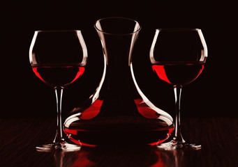 Decanter with wine and glasses in darkness