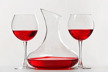 Red wine in glasses and decanter on white background