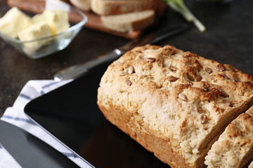 Plate with tasty loaf of beer bread on table