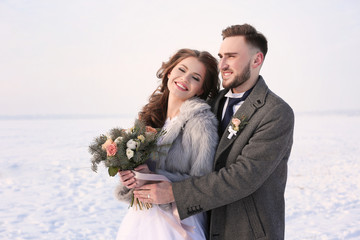 Happy wedding couple outdoors on winter day
