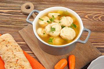 Ceramic pan with delicious chicken and dumplings on wooden cutting board