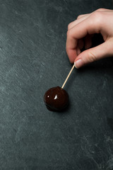 Hand Touching a Chocolate Covered Treat on Stick