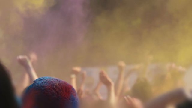 Holi festival, happy people jumping, waving hands and throwing powder paint