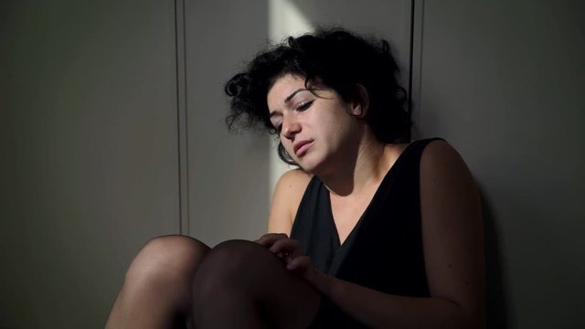 pensive,depressed woman sit in the floor looking the light