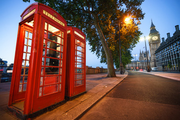 A traditional red phone booth in London with the Big Ben in the background