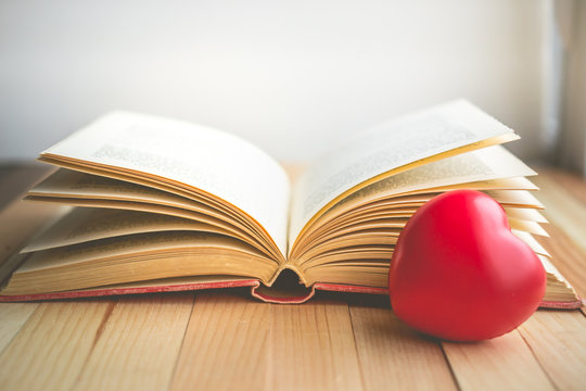 red heart in front of  open book with copy space in relaxation and cozy mood, Image for education, love and brightness  concept