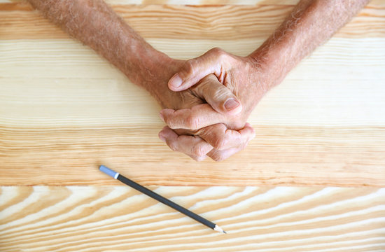 Senior man hands with pencil on table