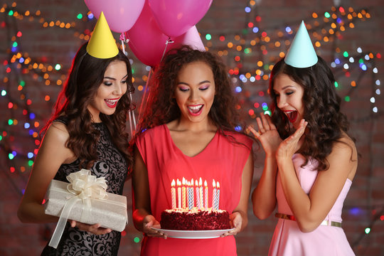 Beautiful young women at birthday party with defocused lights on background