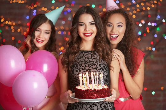 Beautiful young women at birthday party with defocused lights on background