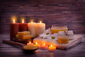 Obraz na płótnie Canvas Beautiful composition of alight candles and honey treatments on wooden table