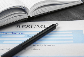 Resume with pen and notebook on table, closeup