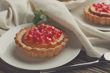 Tasty tart with fresh seeds of pomegranate served on plate