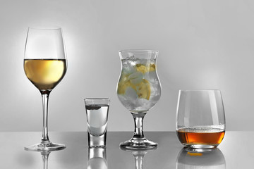 Glasses of wine and spirits on light background