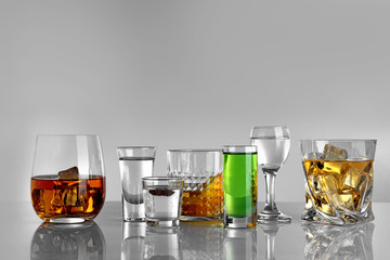 Glasses of wine and spirits on light background