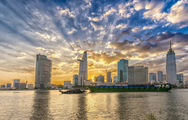 Fototapeta na wymiar Ho Chi Minh City, Vietnam - February 14th, 2017: Riverside City sunset clouds in the sky at end of day brighter coal sparkling skyscrapers along beautiful river in Ho Chi Minh City, Vietnam