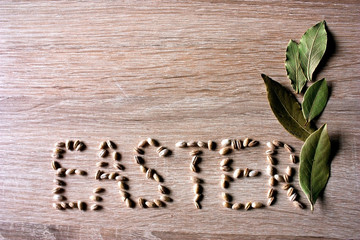 Easter Inscription from grains on wooden background with green leaves
