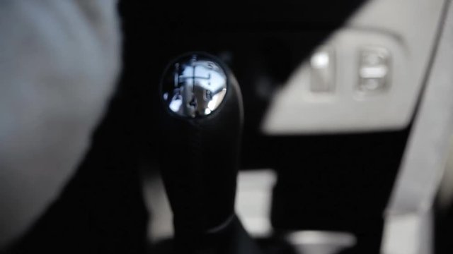 Shifting the gearshift from number one to five; female hand.
