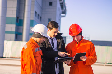 boss or Chief  instructs young team of  young engineers with a construction project on tablet. Technology in work.  Business modern background