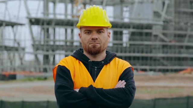 Serious construction worker crosses his arms and stares at the camera