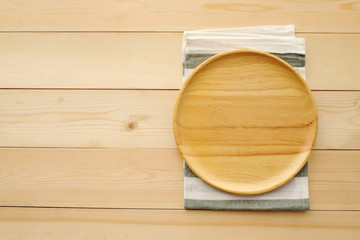 Empty round wooden tray and napkin on table, top view, flat lay, food display montage background with copy space