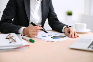 Business woman sitting at the table and examines the financial results