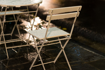 Wet coffee table and chairs after heavy rain at night